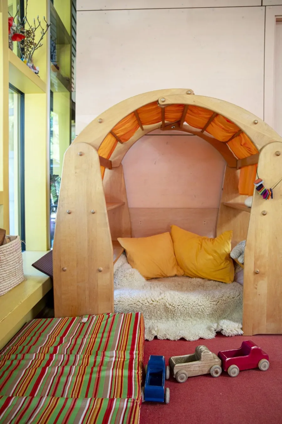 Hölzerne Kuschelhöhle mit Kissen und Schaffell in der Kinderstube