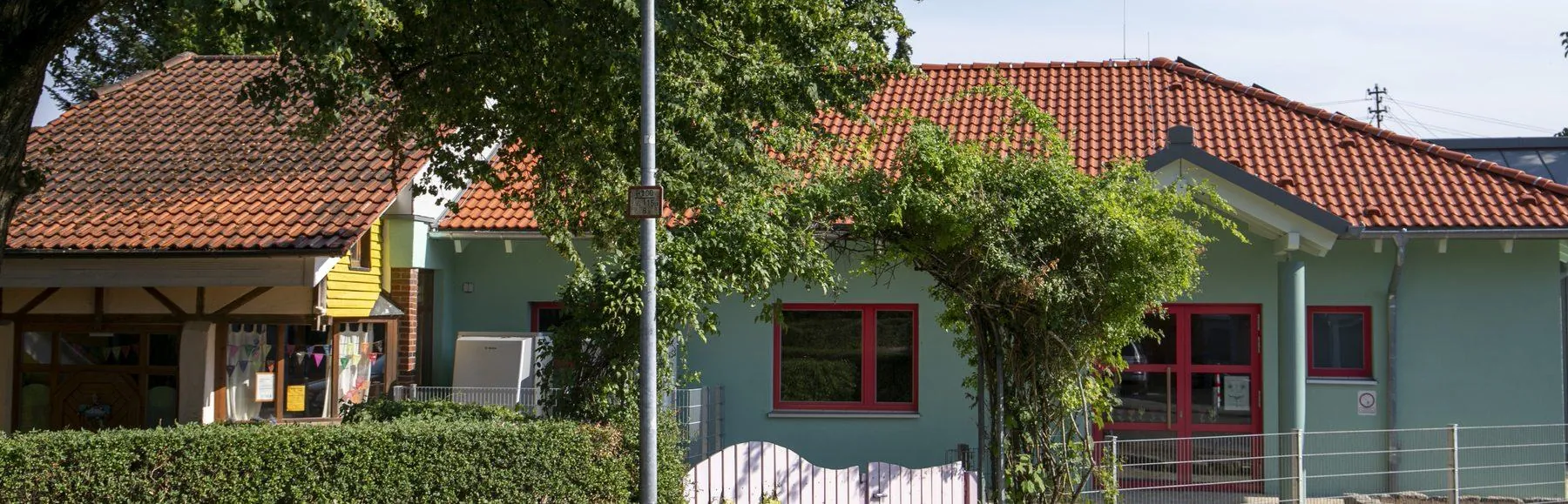 Der Waldorfkindergarten Großdeinbach von der Straße aus, mit Hecke und rosa Gartentor