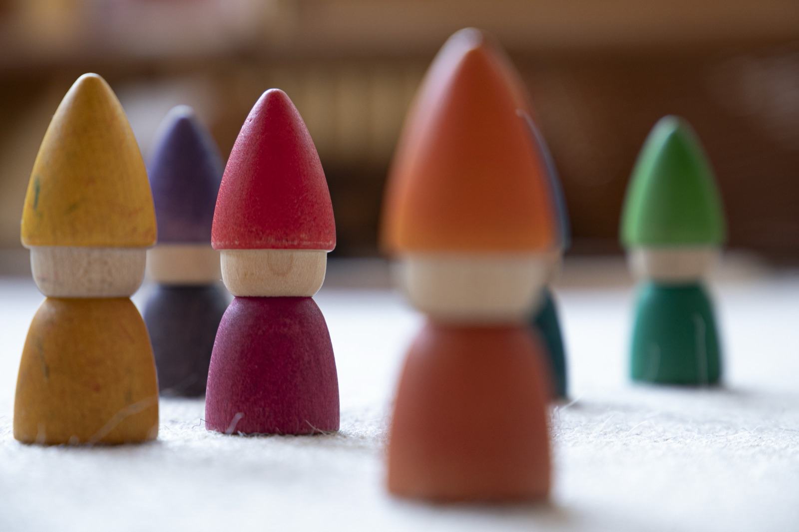 Bunte Holzwichtel in Gelb, Rot, Orange und Grün auf einem hellen Tuch