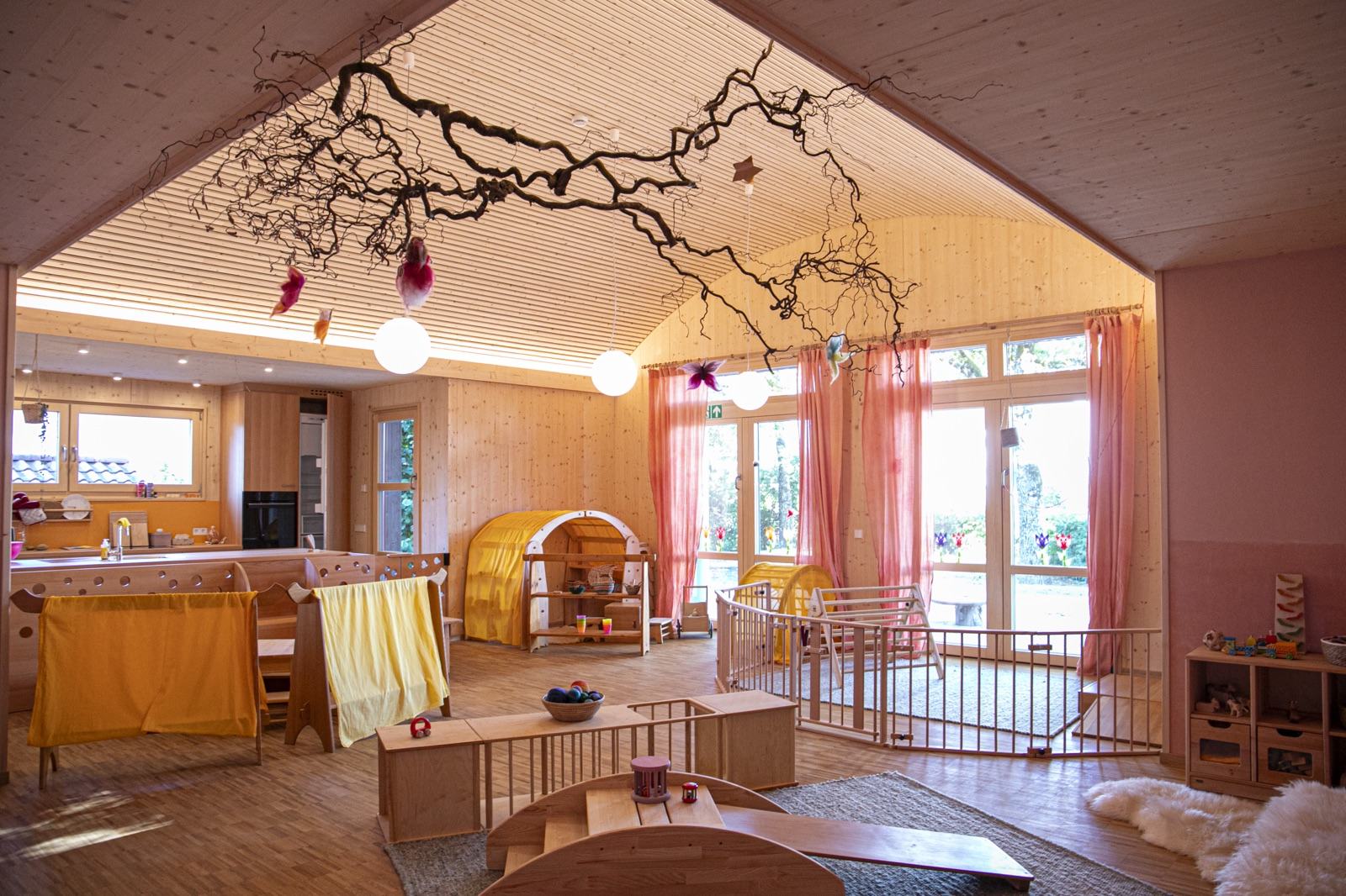 Lichtdurchfluteter Gruppenraum der Krippe in Großdeinbach mit Astdekoration an der Decke