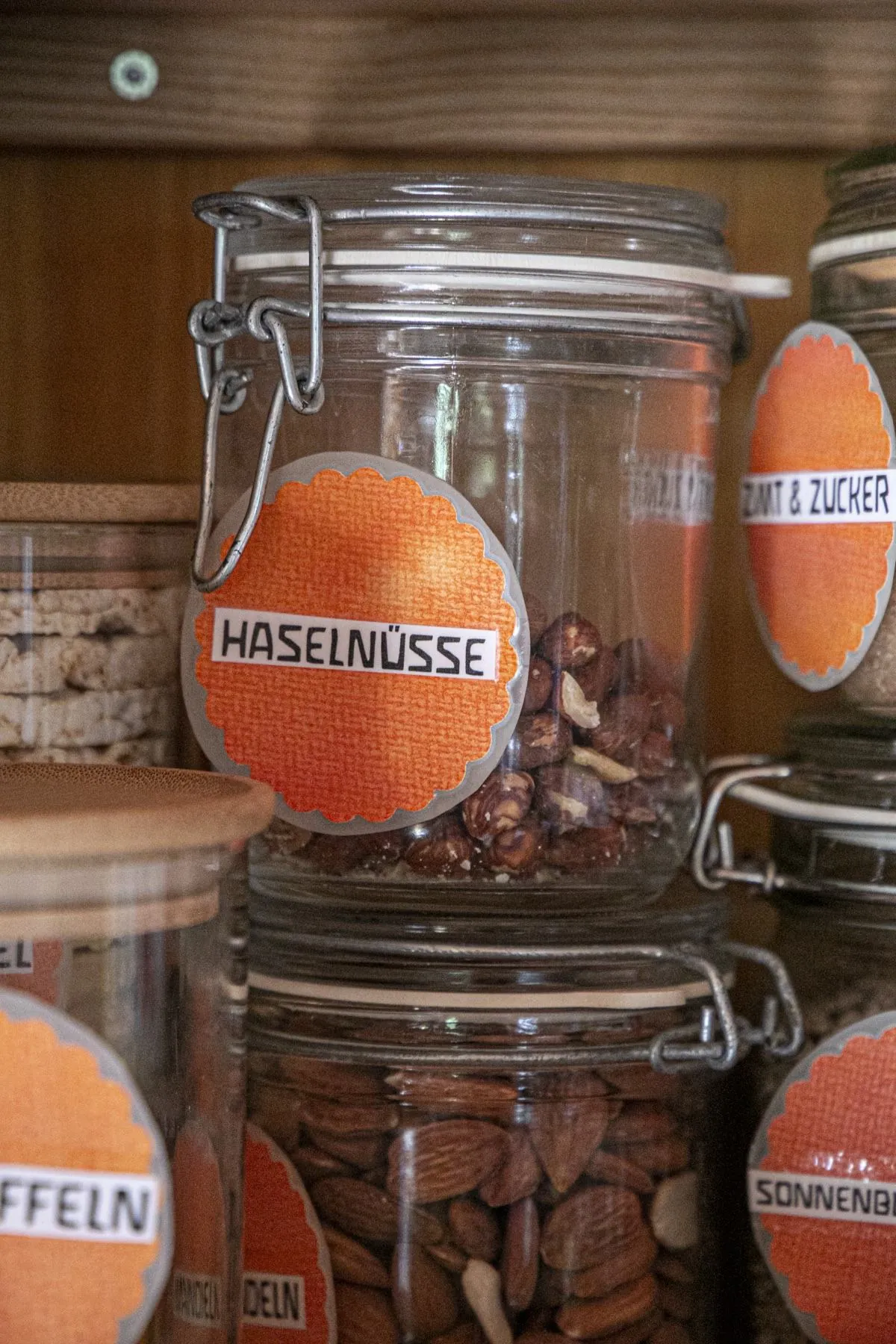 Vorratsgläser mit Haselnüssen und Mandeln, beschriftet mit bunten Etiketten